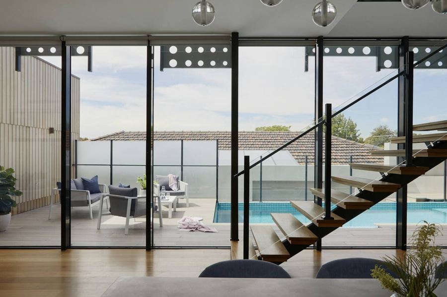 A light filled room with floor to ceiling glass doors opening to a pool and terrace