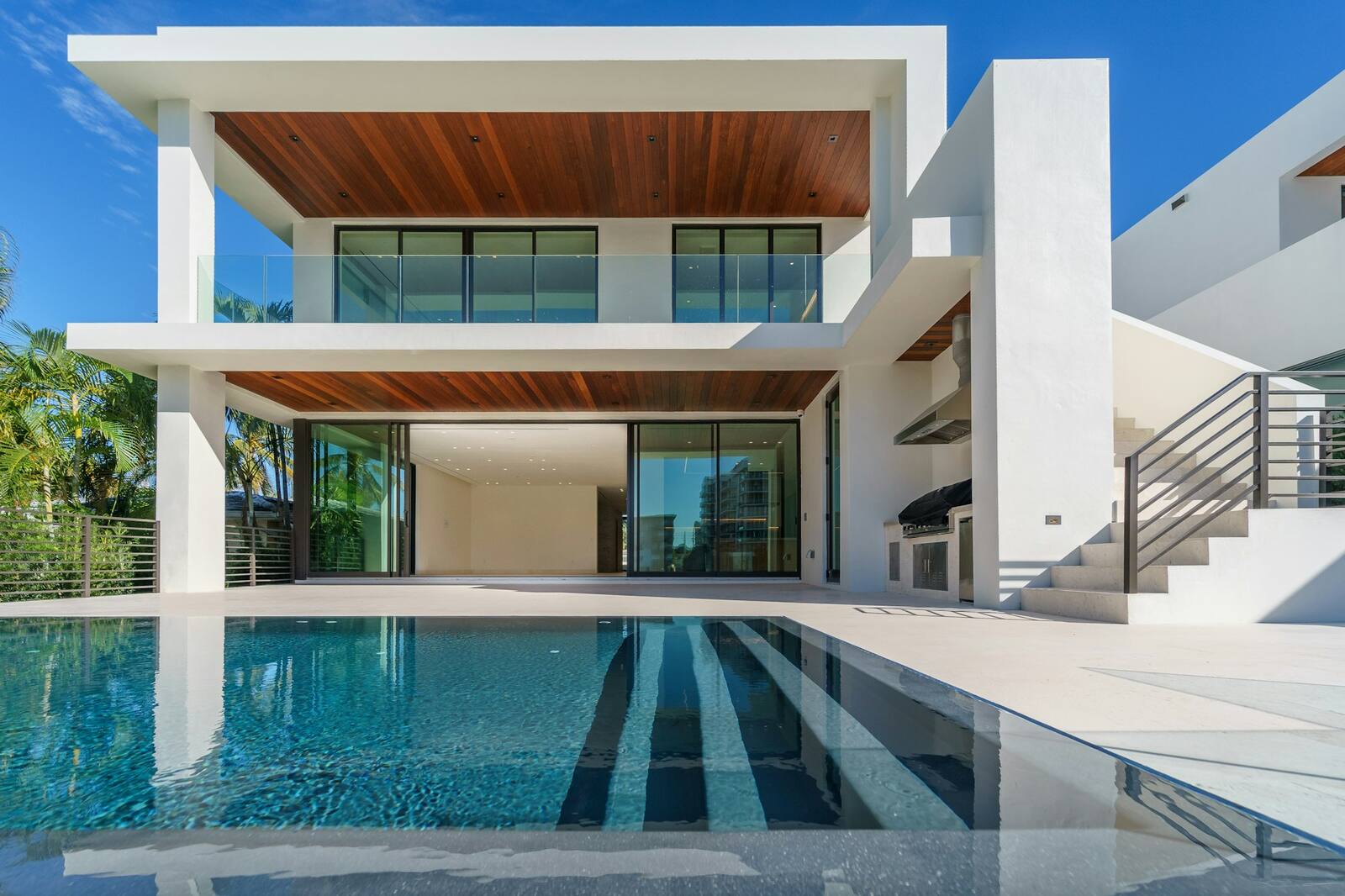 A white contemporary home with a pool and tropical planting
