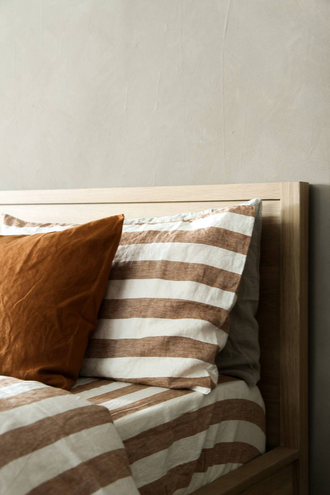 Striped and solid linen pillows layered on a bed